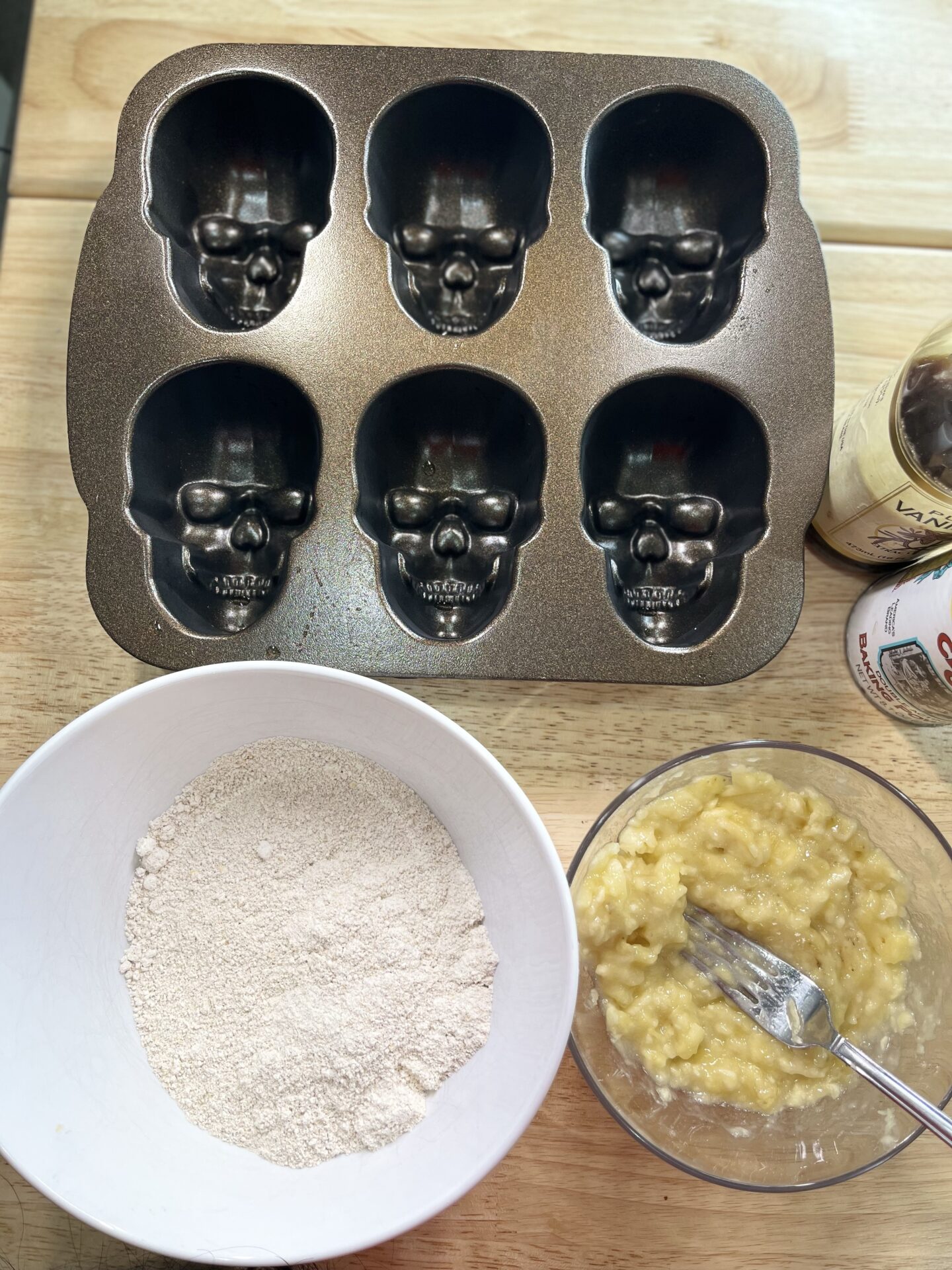 skull baking mold next to a bowl with oat flour and a bowl with mashed banana