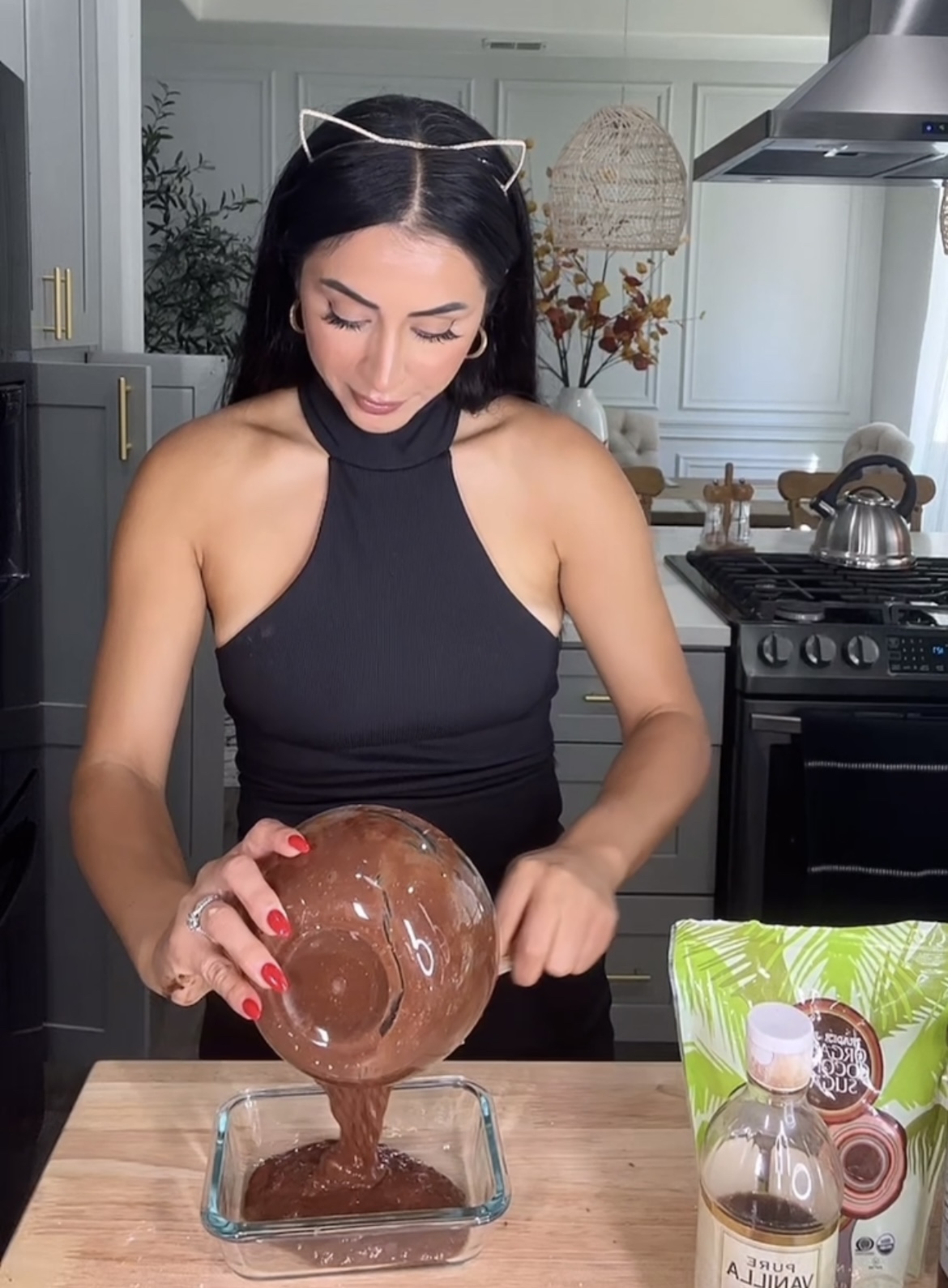 woman wearing cat ears pouring brownie batter in a bowl