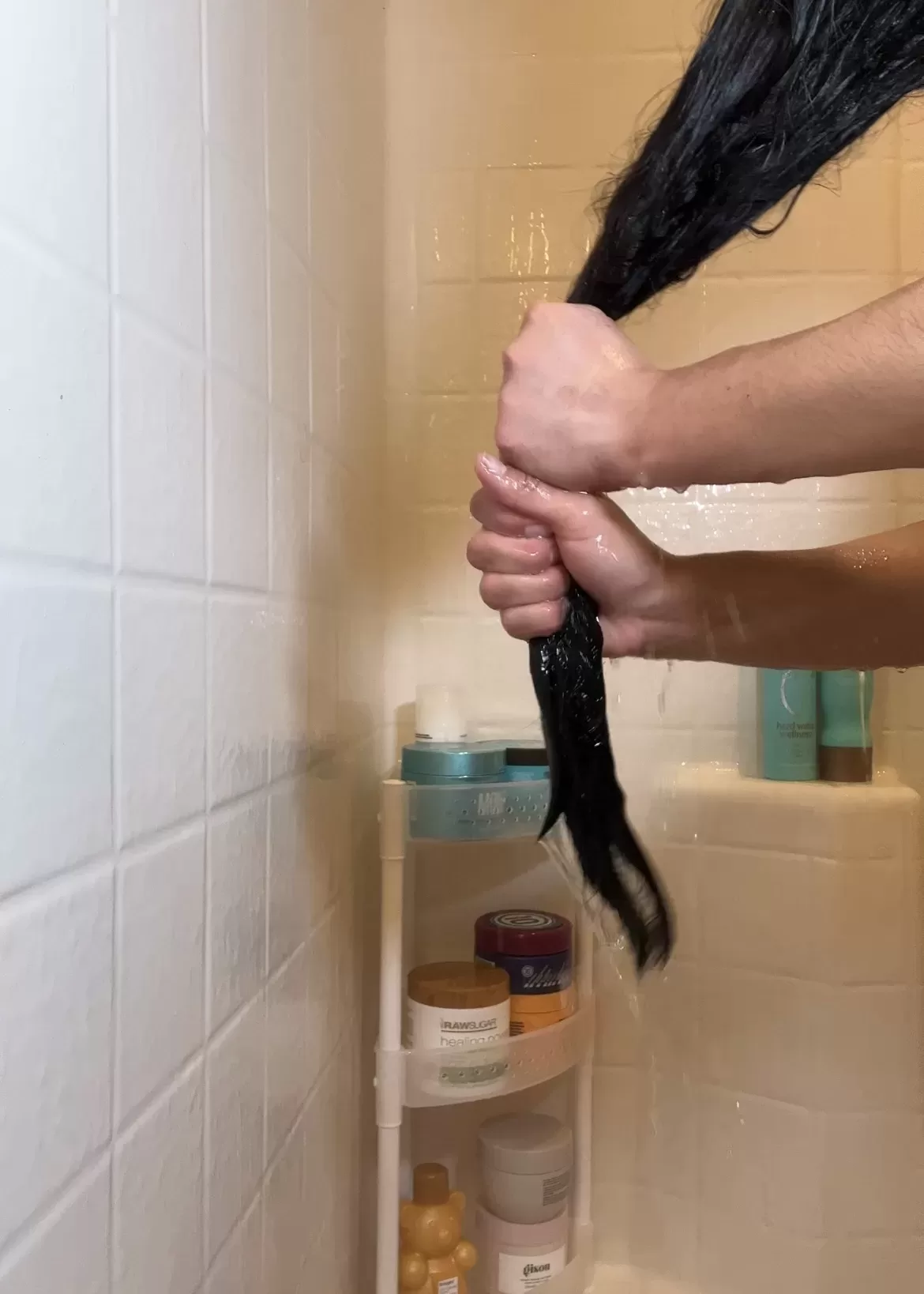 woman wringing water out of her long hair in the shower