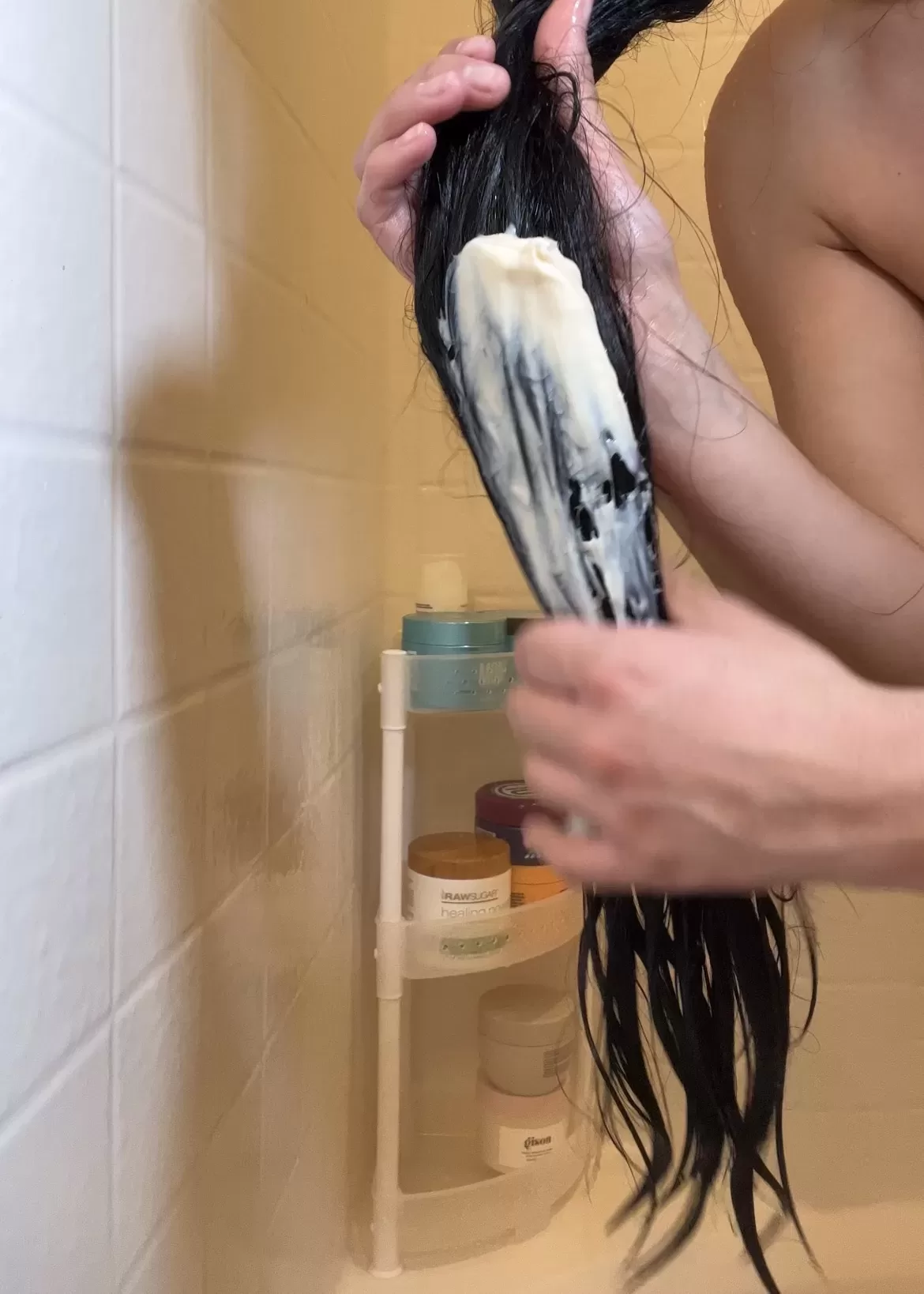 woman applying  Briogeo Vegan Apple Honey Deep Conditioning Hair Mask to her long hair in the shower