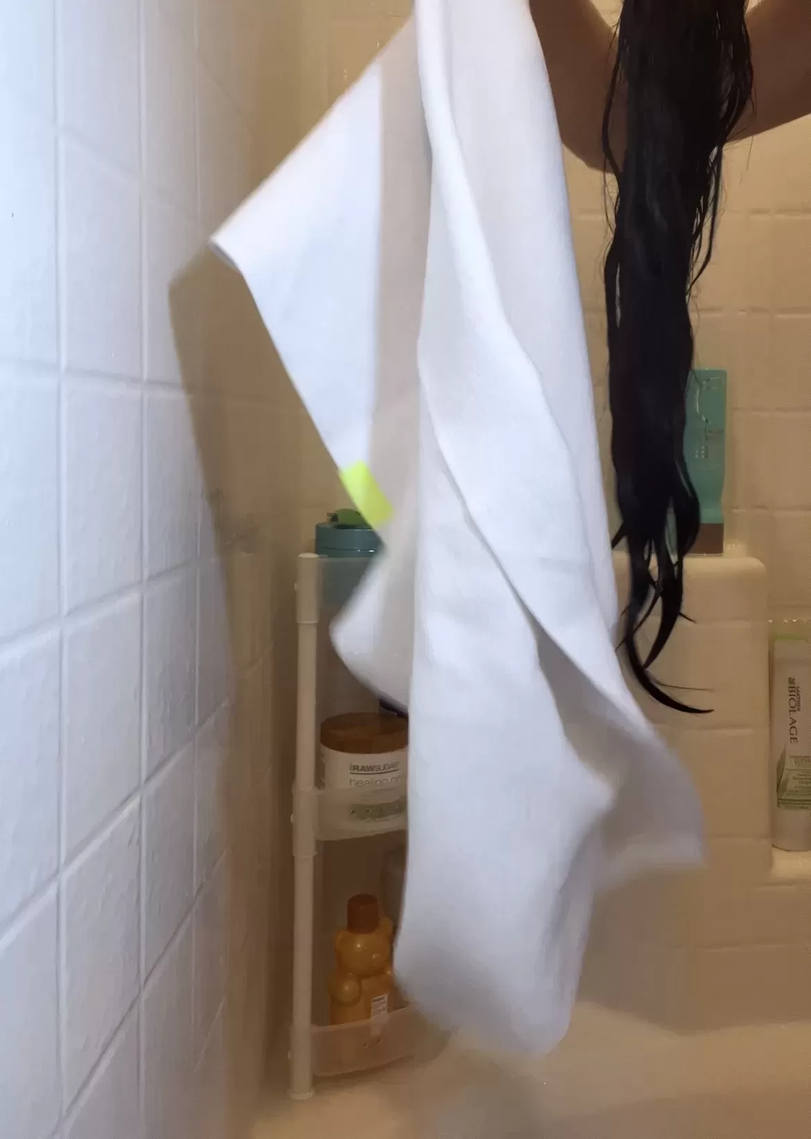 white microfiber towel in the shower next to long dark hair 